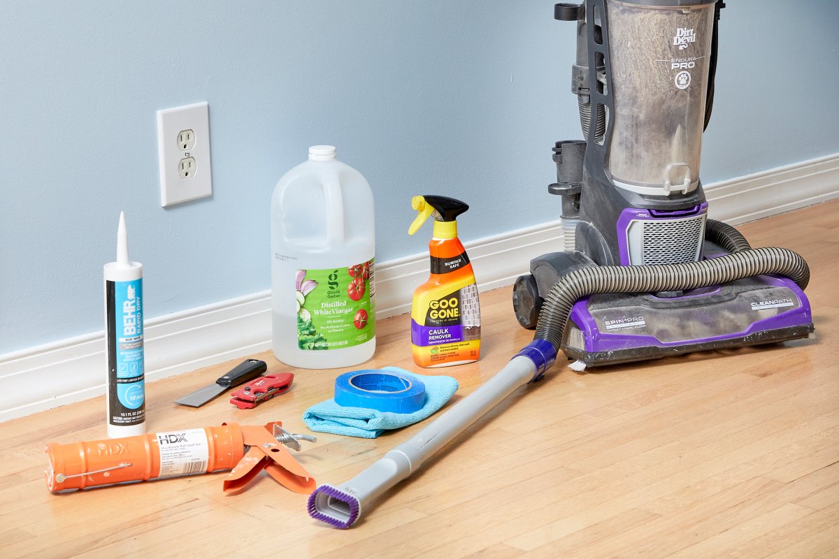 Materials need to caulk baseboards, including a vacuum, caulk, and painter's tape.