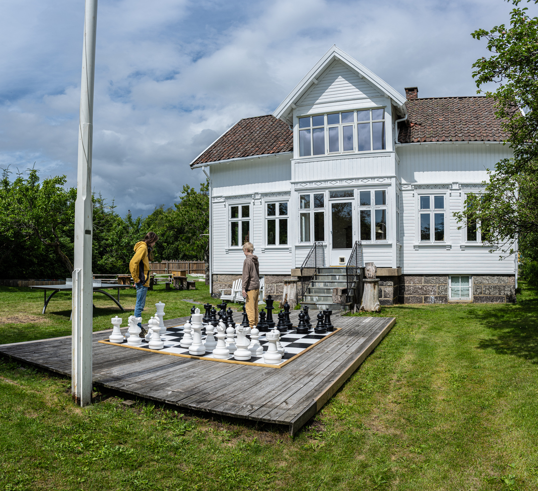 Two kids playing large garden chess.