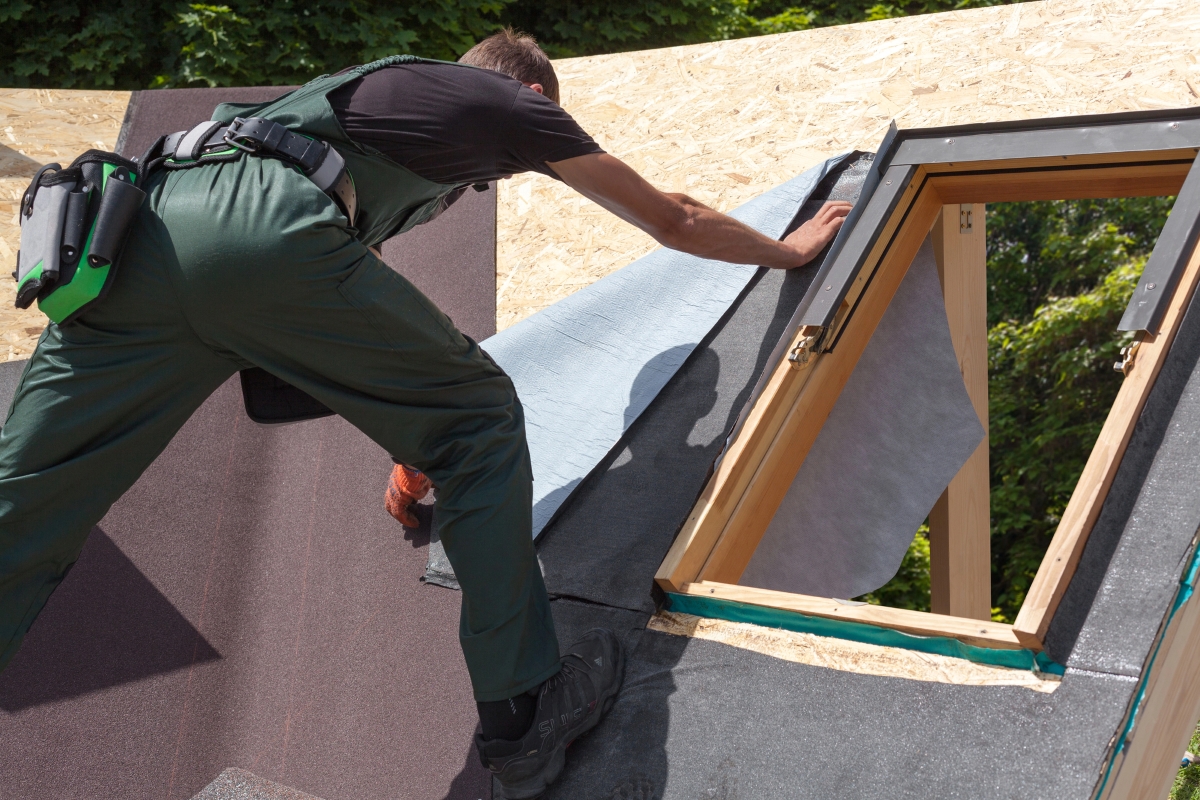 A roofer installing material around skylight.