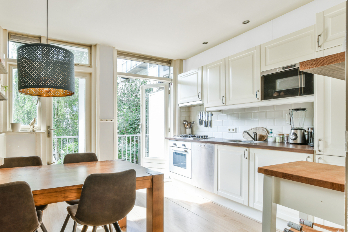 A small kitchen and dining room with white walls and cabinets.