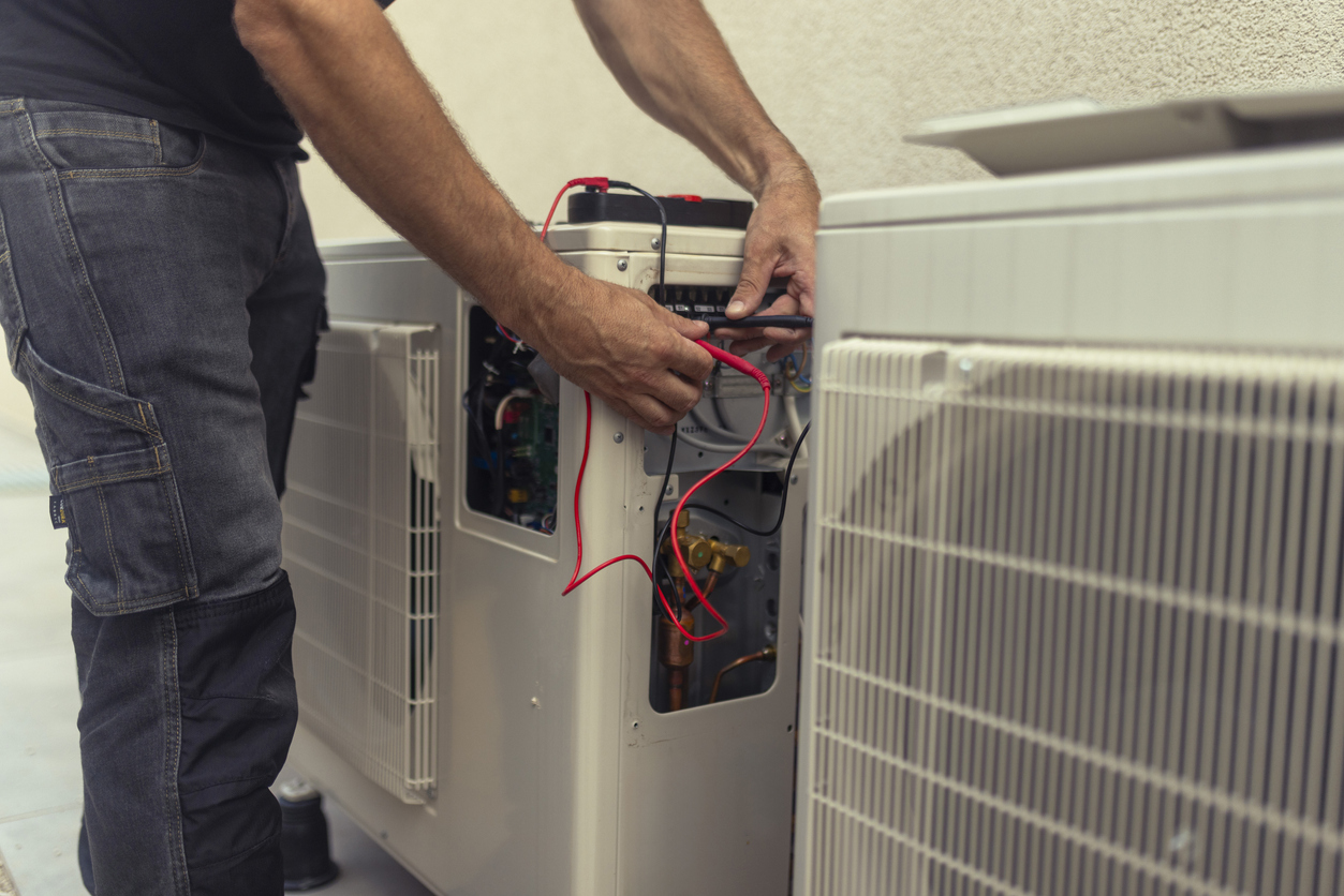 Electrician installs heat pump for energy savings.