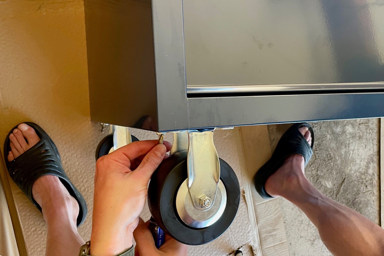 A person installing the wheels on the Husky Standard Duty 9-Drawer Mobile Workbench Cabinet during testing.