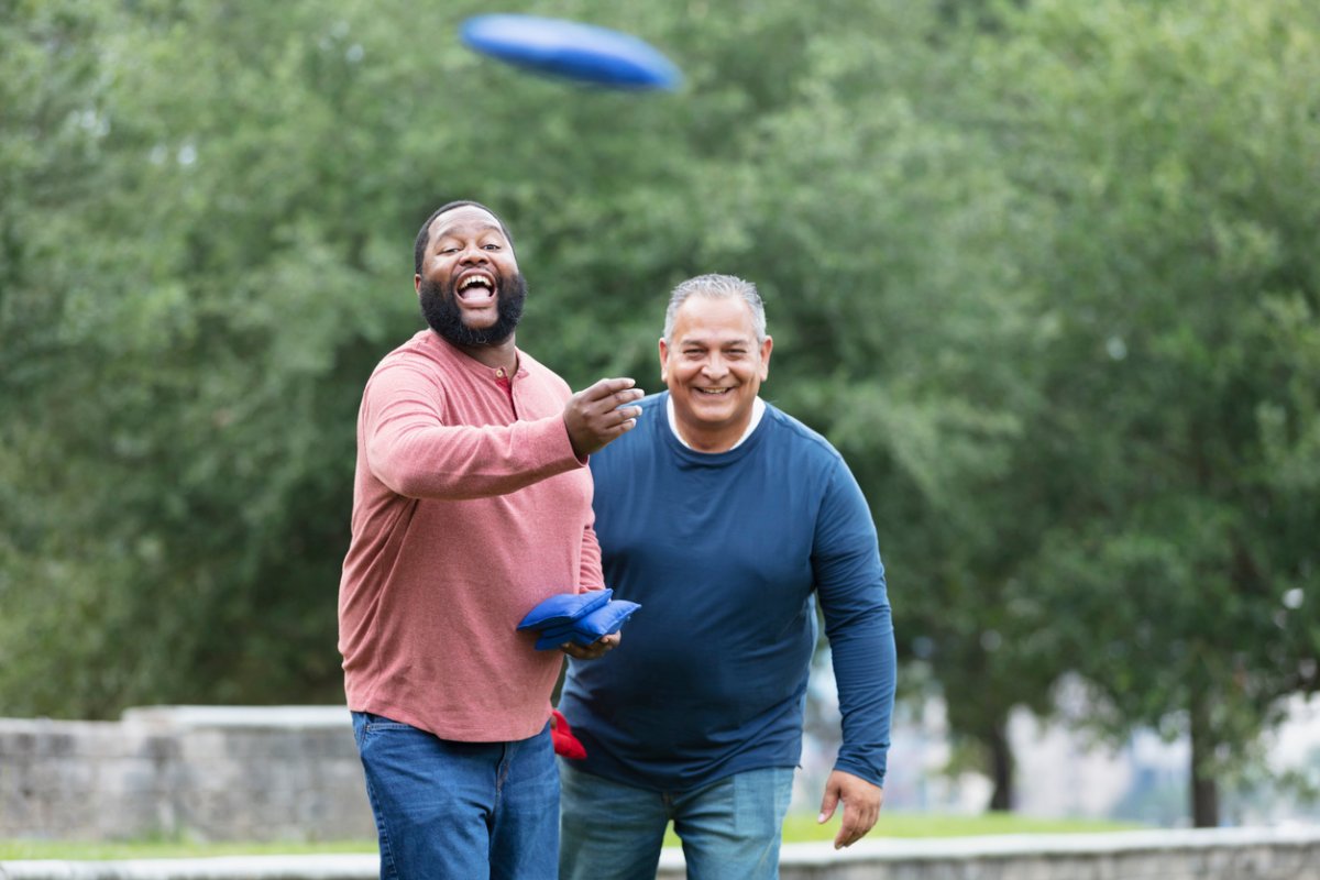 Two men having fun playing a cornhole game.