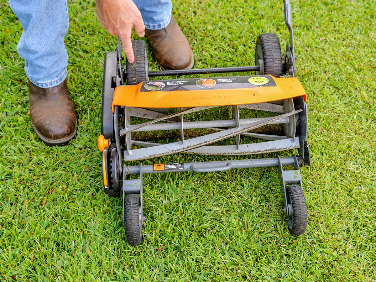 A person making an adjustment to the blades of the Fiskars StaySharp Max reel mower