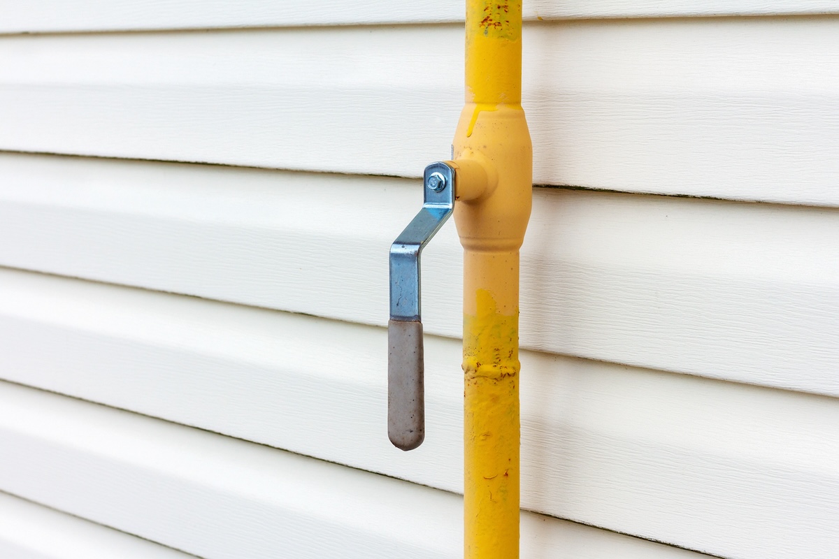 A yellow natural gas line installed along the exterior of a residential home.