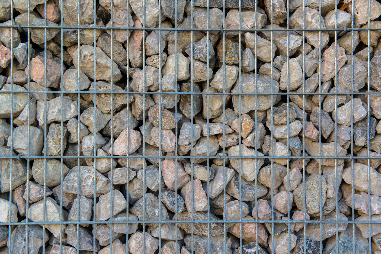 Gros plan d'un mur de soutènement en gabion constitué d'un enrochement et d'une armature métallique.