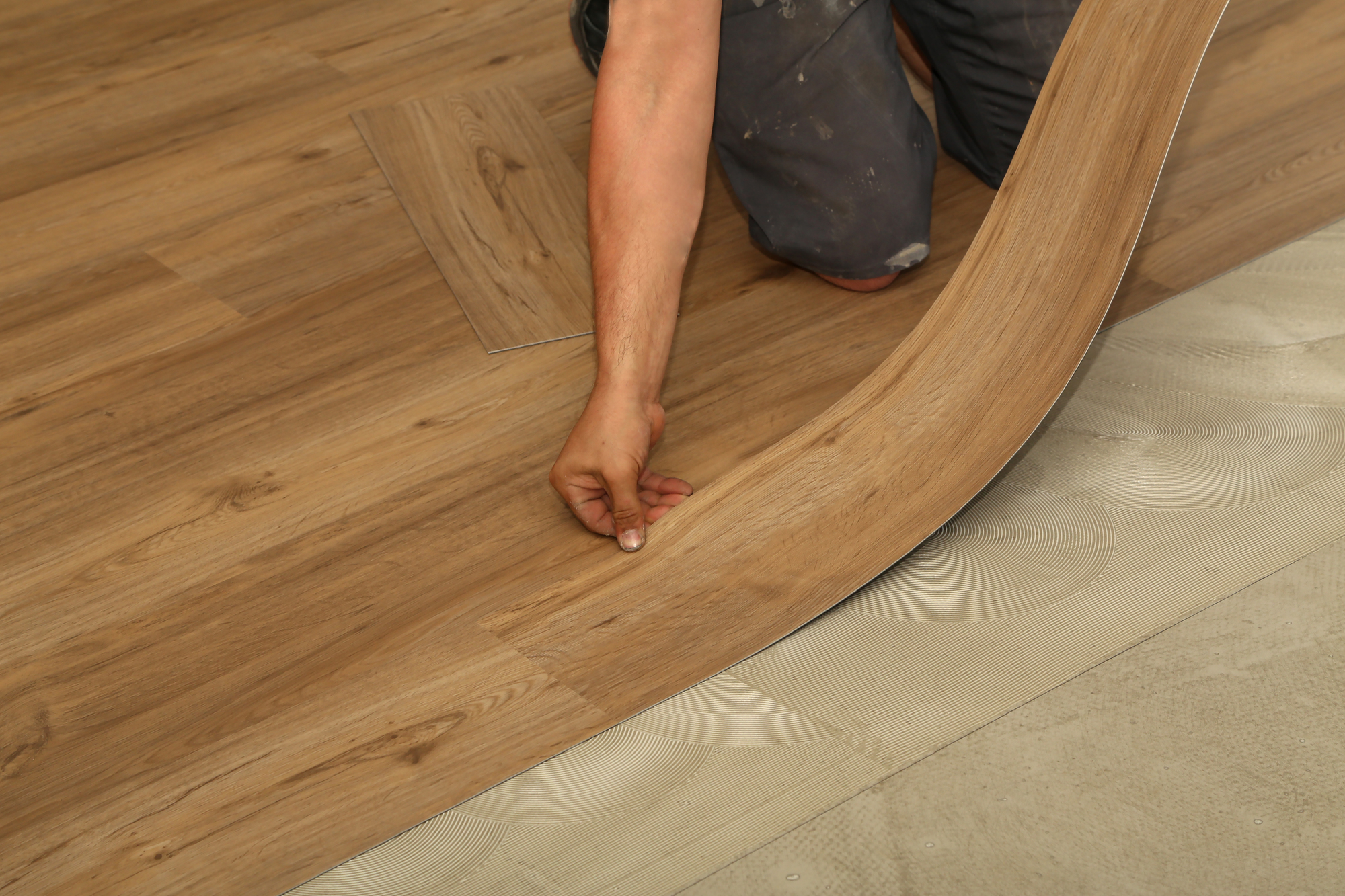 A person installing new wood-look vinyl tiles on floor