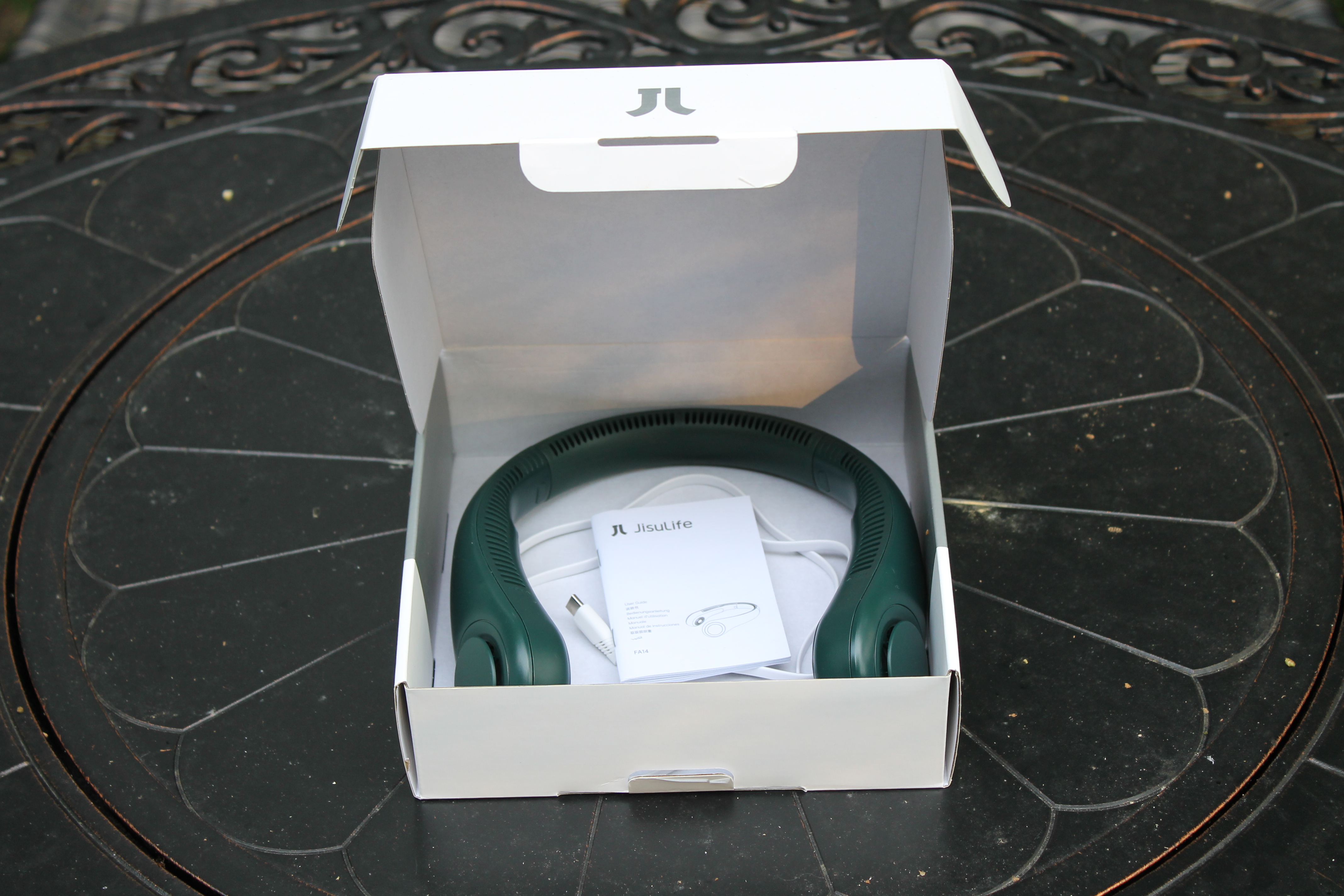 Green Jisulife Portable Neck Fan in its box with manual and charging cord