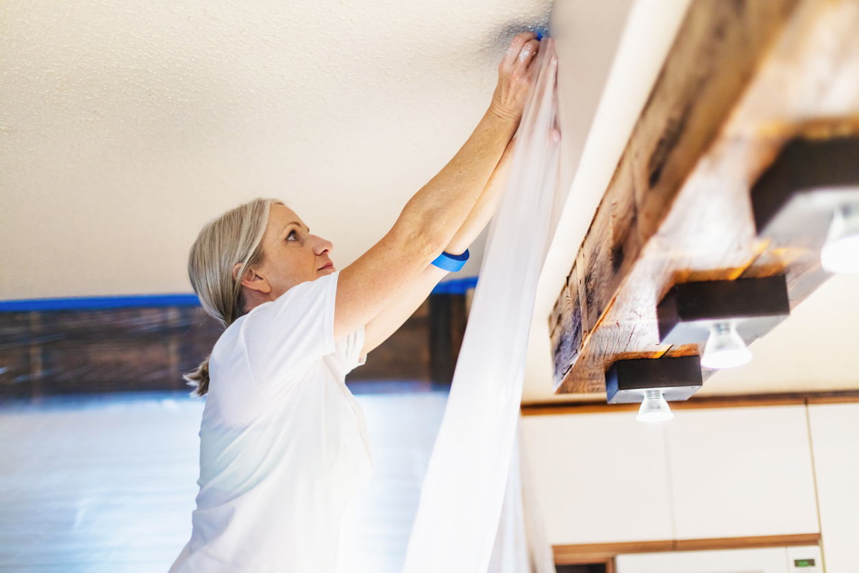 Adult Female Using Painter's Tape and Plastic for Painting Preparation; Private Residence Remodel.