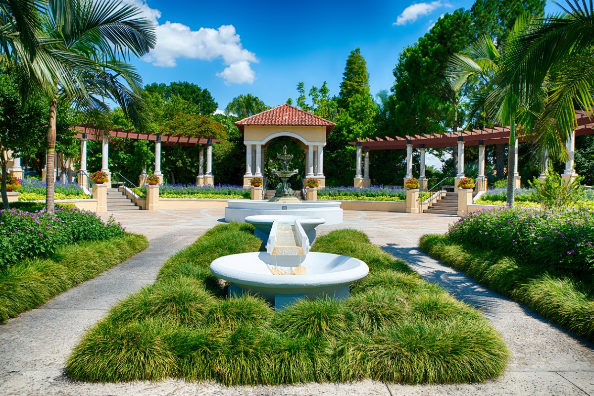 Vue de la fontaine dans un parc public avec un paysage herbeux et des arbres.