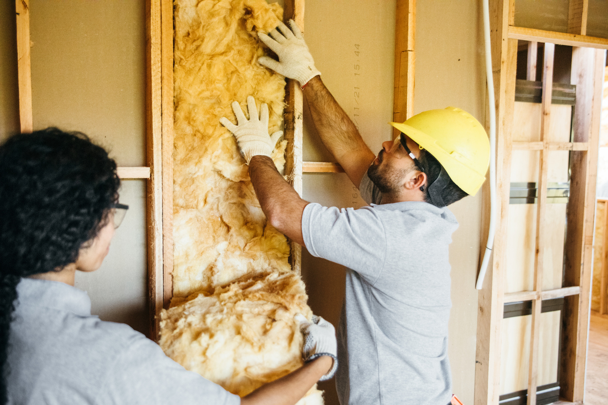 Construction workers in attic fitting insulation