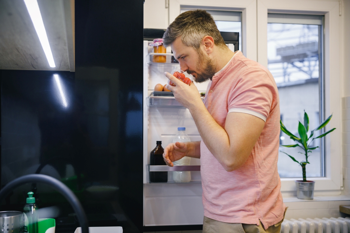 Homme sentant des tomates dans le réfrigérateur