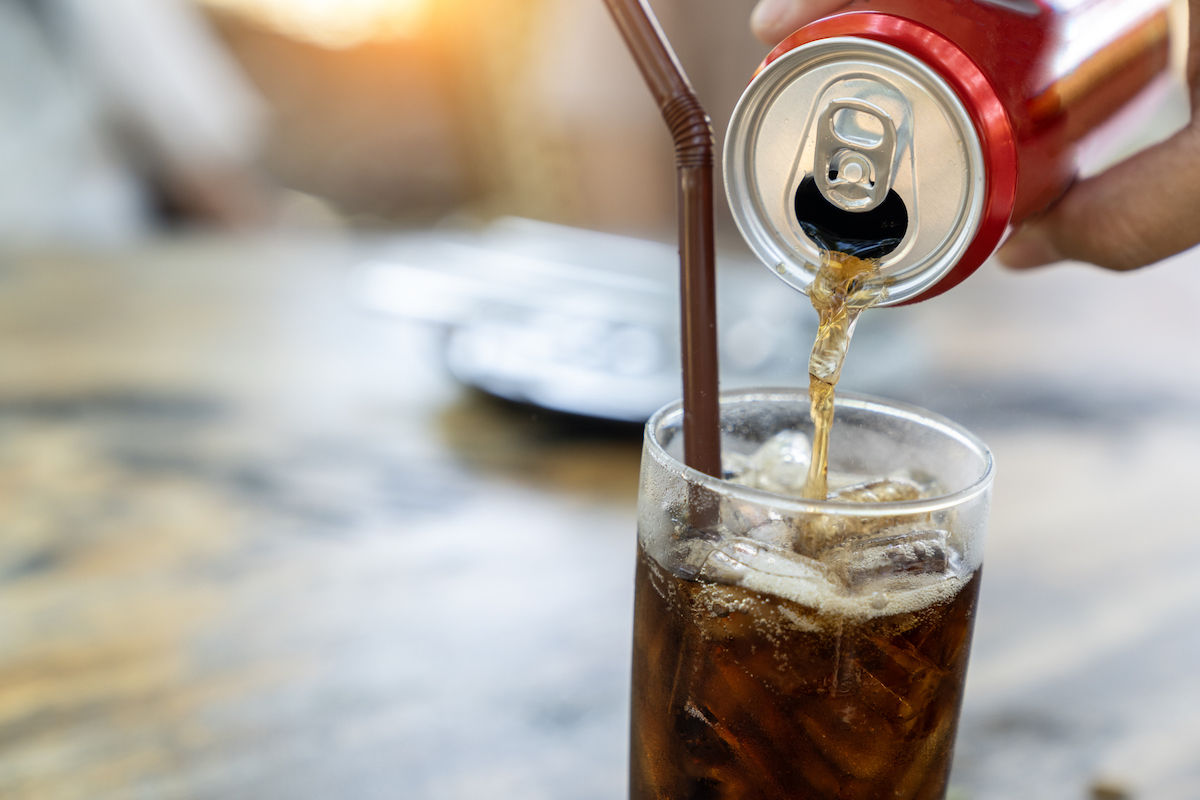 Pouring cola from a can into a glass.