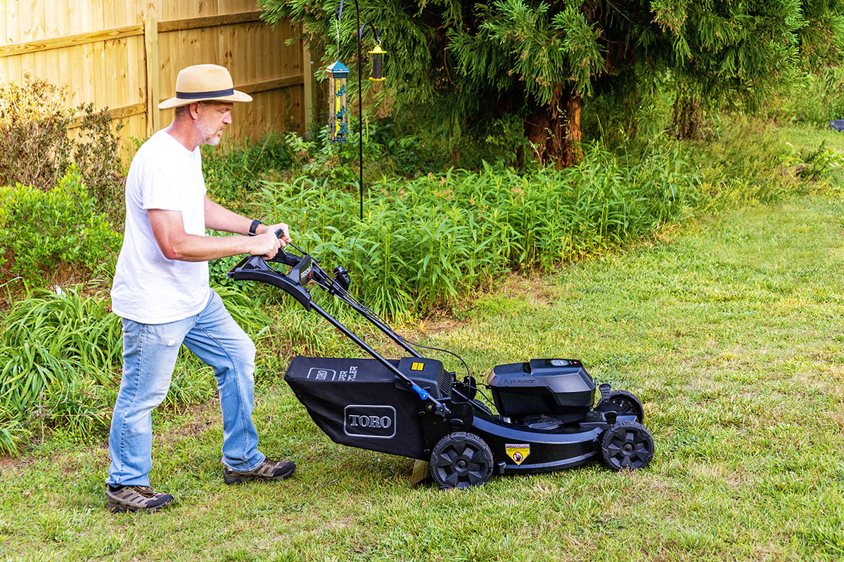 Un homme qui pousse la meilleure tondeuse à gazon pendant qu'il tond son jardin