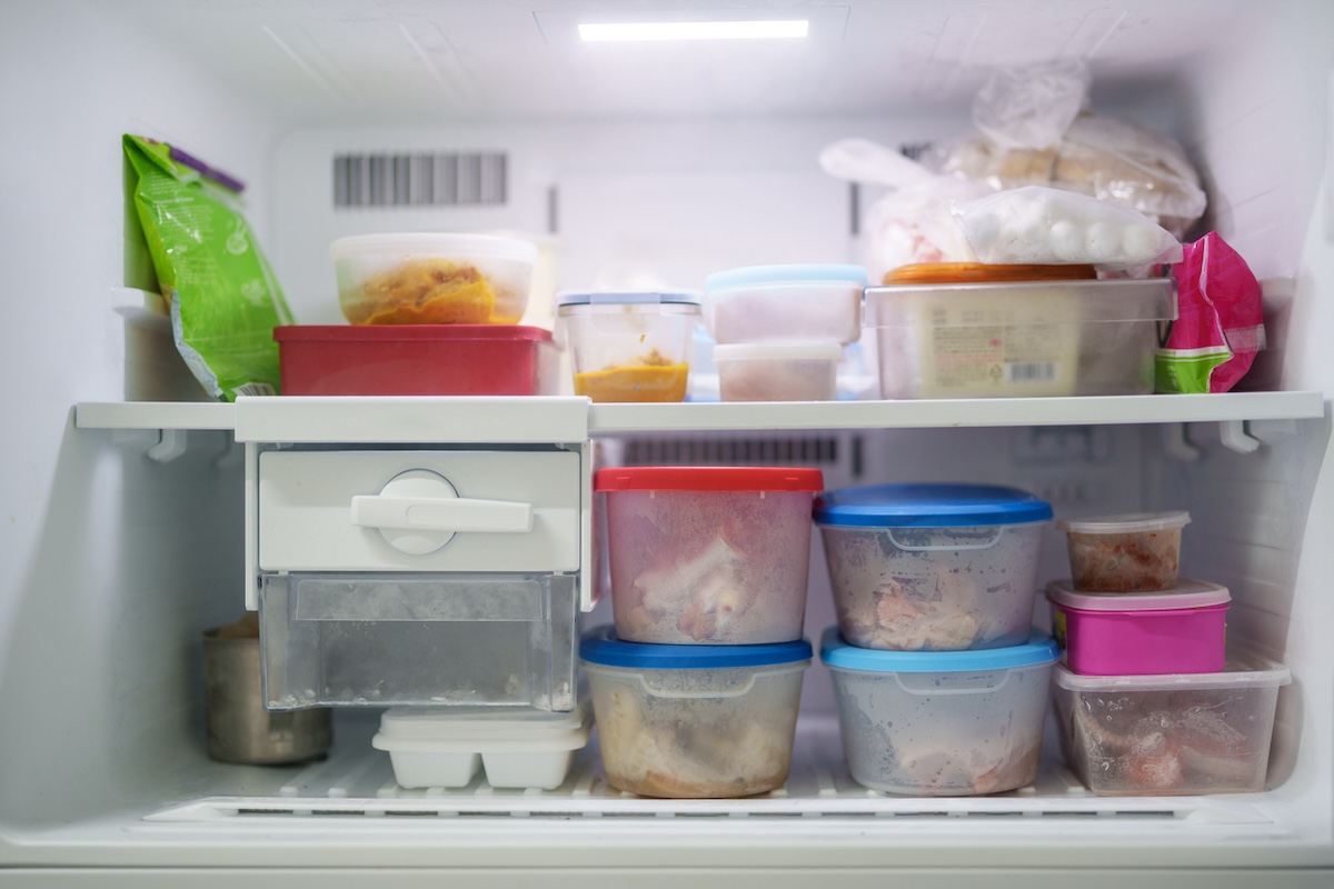 Freezer filled with with containers and bags of frozen food. 