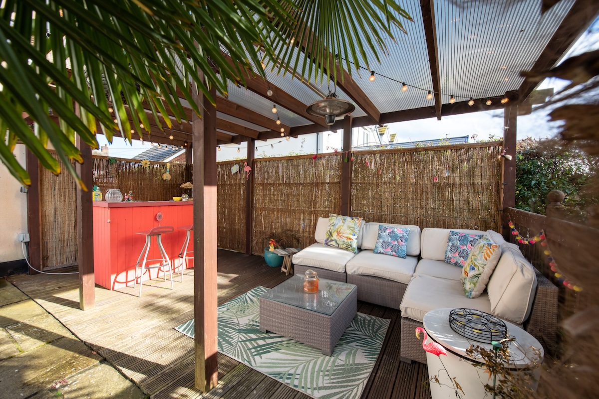 Une cabane dans l'arrière-cour avec des meubles de patio et un bar tiki rouge.