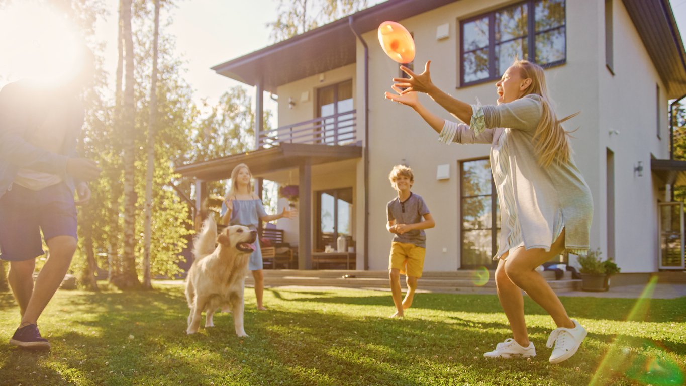 Une famille jouant au frisbee sur la pelouse avec son chien.