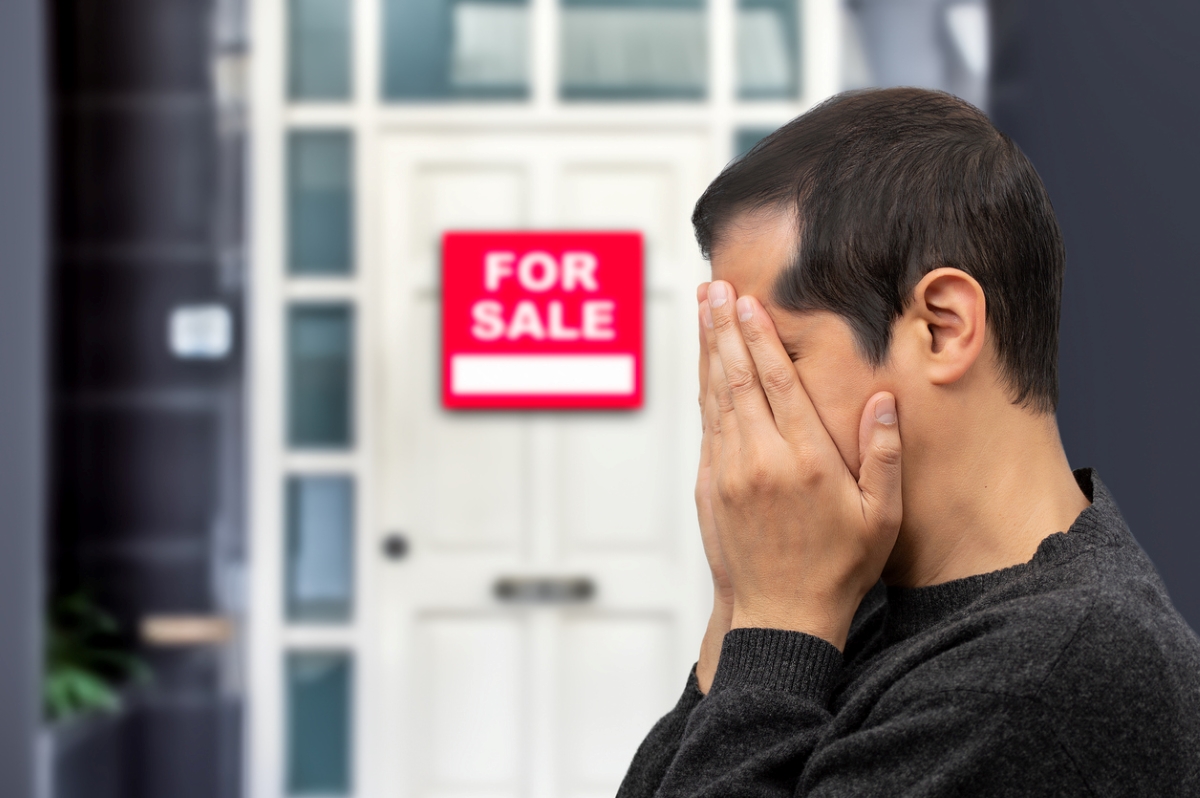 Un homme bouleversé en voyant un panneau de vente sur sa porte