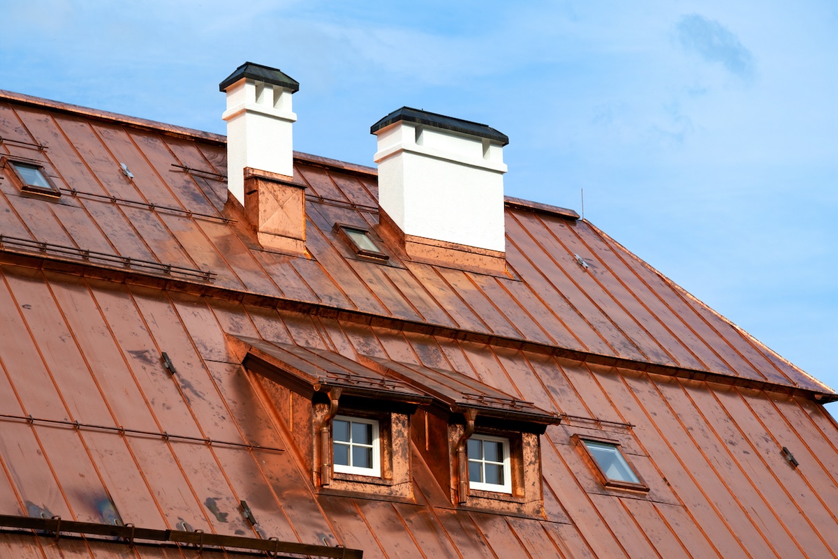 A home with a large copper roof against a blue sky. 