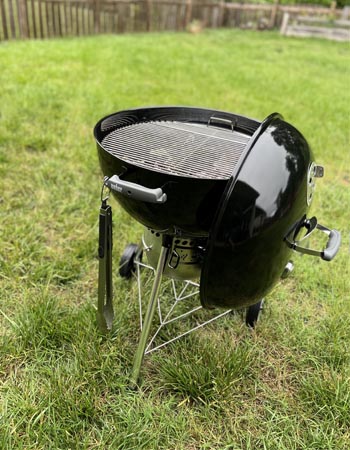 The Weber Original Kettle Premium charcoal grill set up for use in a yard