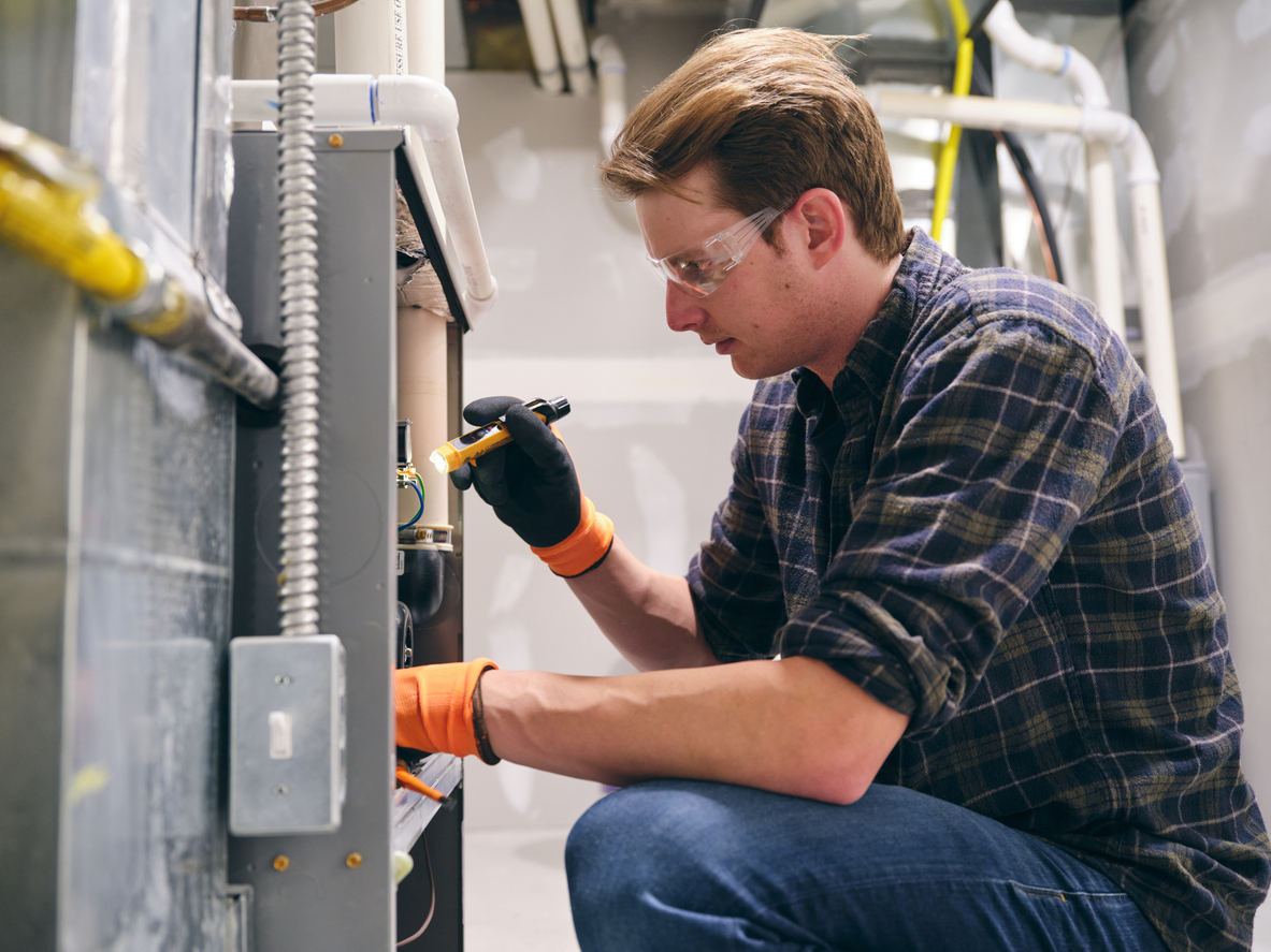 A repairman working inside a home, repairing a furnace.