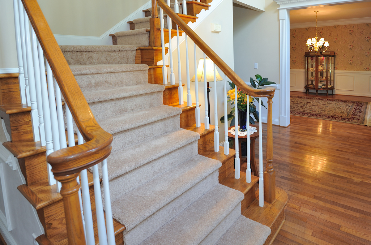 A Hollywood style carpeted staircase leads into the foyer of a home.