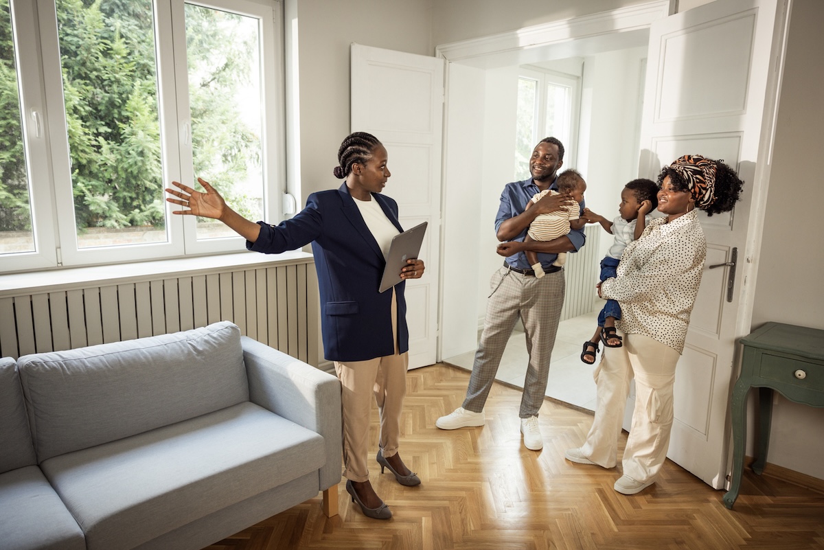 Real estate agent showing open house to young couple with infant and toddler. 