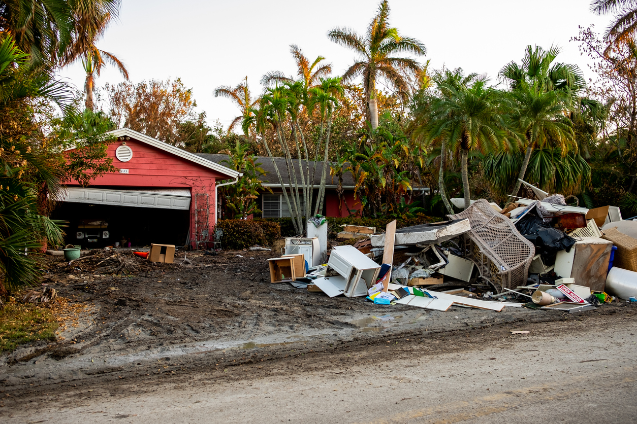 home wreckage in the aftermath of a hurricane pile of furniture on front lawn