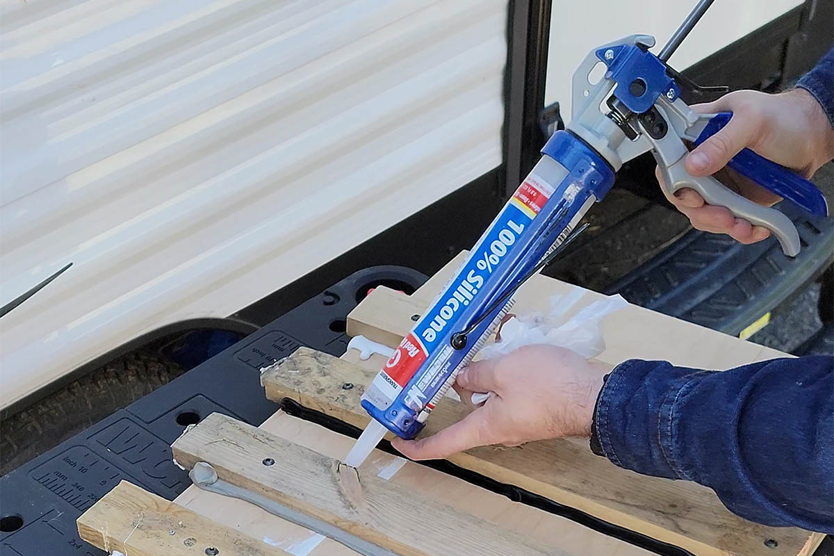 Une personne utilisant le meilleur calfeutrage extérieur pour sceller un morceau de clôture en bois.