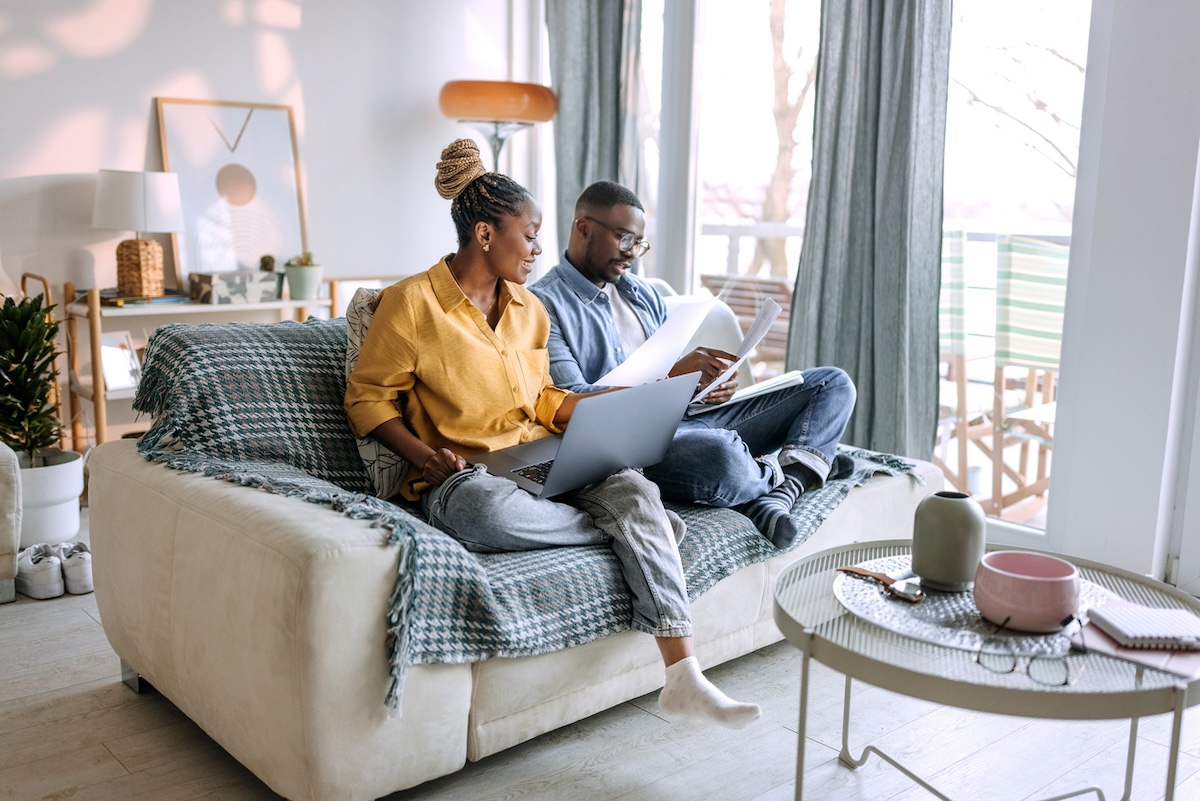 A couple sitting on the couch organizing their remodeling expenses and filing taxes and claiming tax credits.