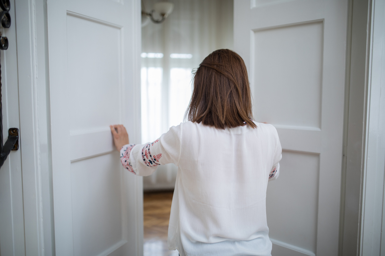 A view from behind of a woman opening doors into a large room.