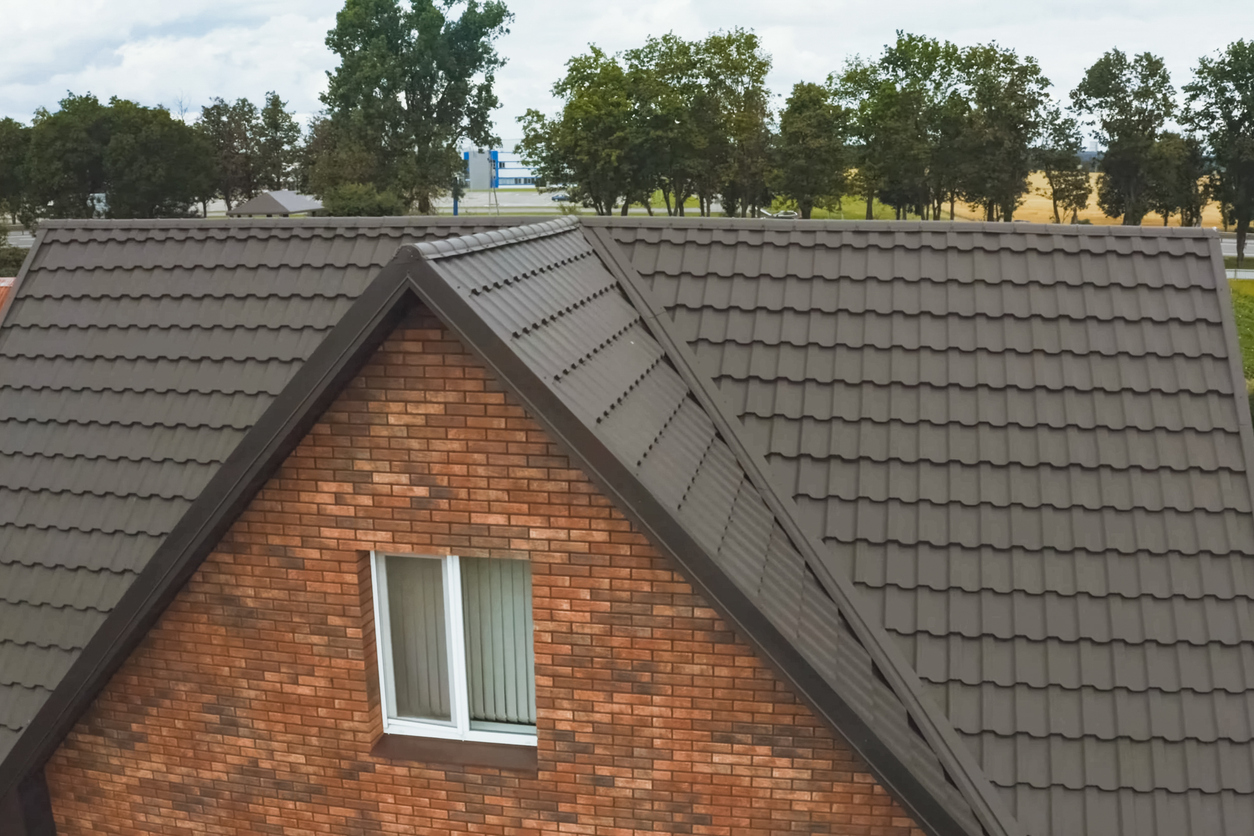 Modern roof made of metal. Corrugated metal roof and metal roofing. House with a brown metal roof.