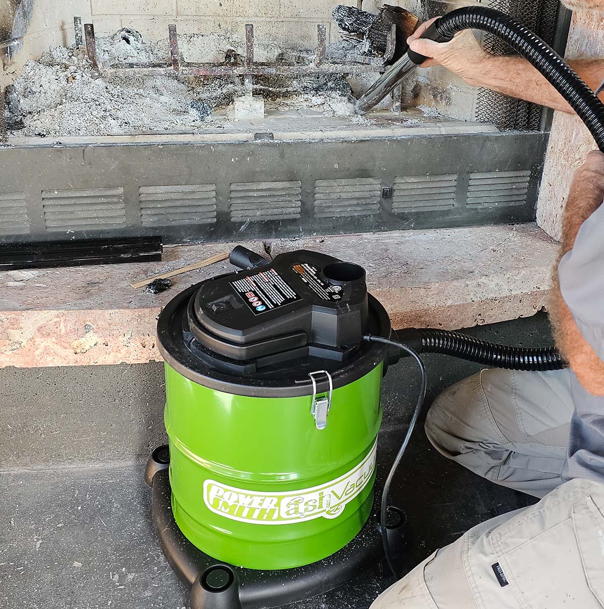 Une personne utilisant l'aspirateur à cendres PowerSmith pour nettoyer un foyer.