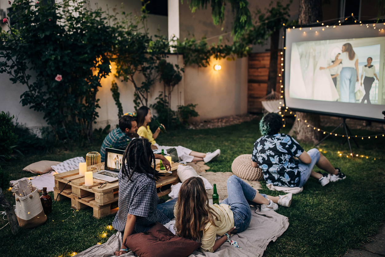 Friends watching movie on the video projector in the backyard garden