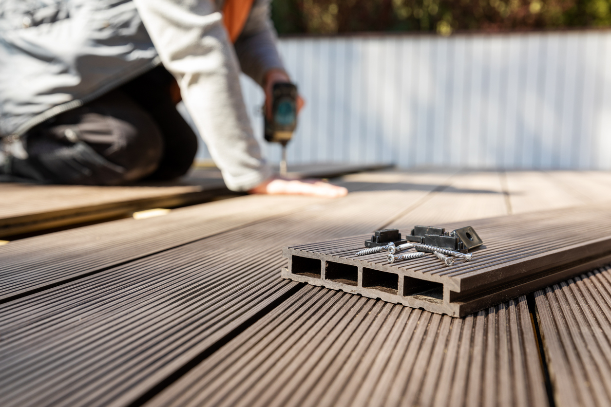 wpc terrace construction - worker installing wood plastic composite decking boards