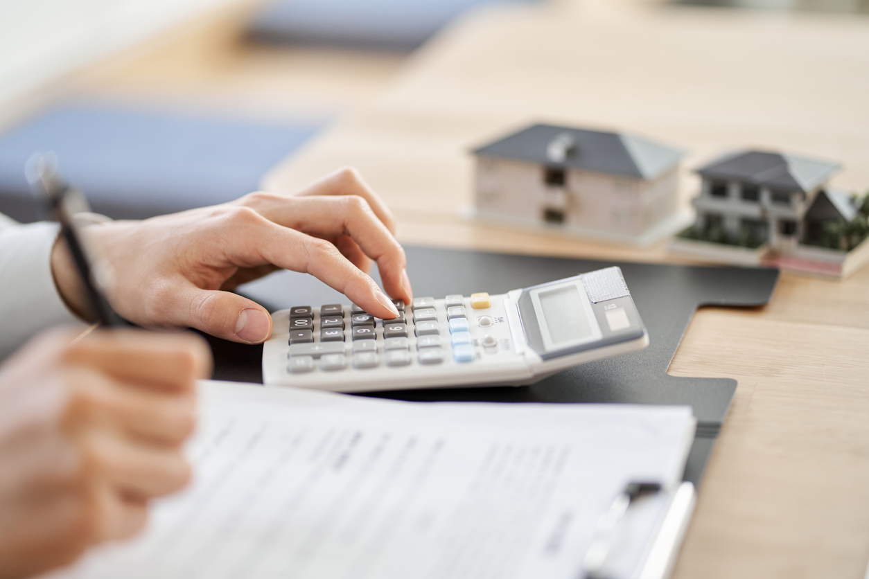 les mains d'un homme au bureau utilisant une calculatrice avec un contrat de prêt sur le bureau