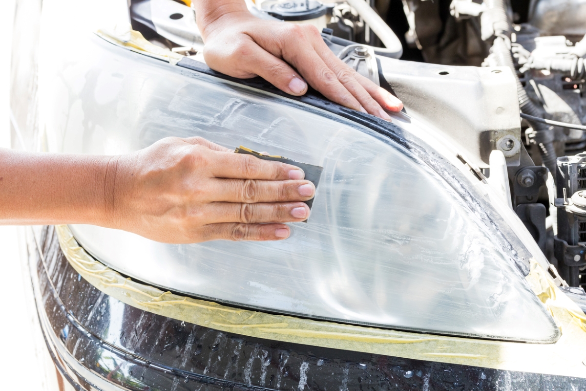 Person rubbing white paste off headlight