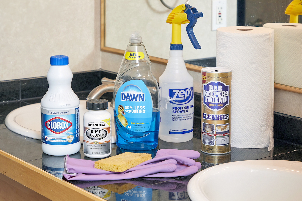 Materials needed to clean a porcelain sink assembled on a bathroom counter.