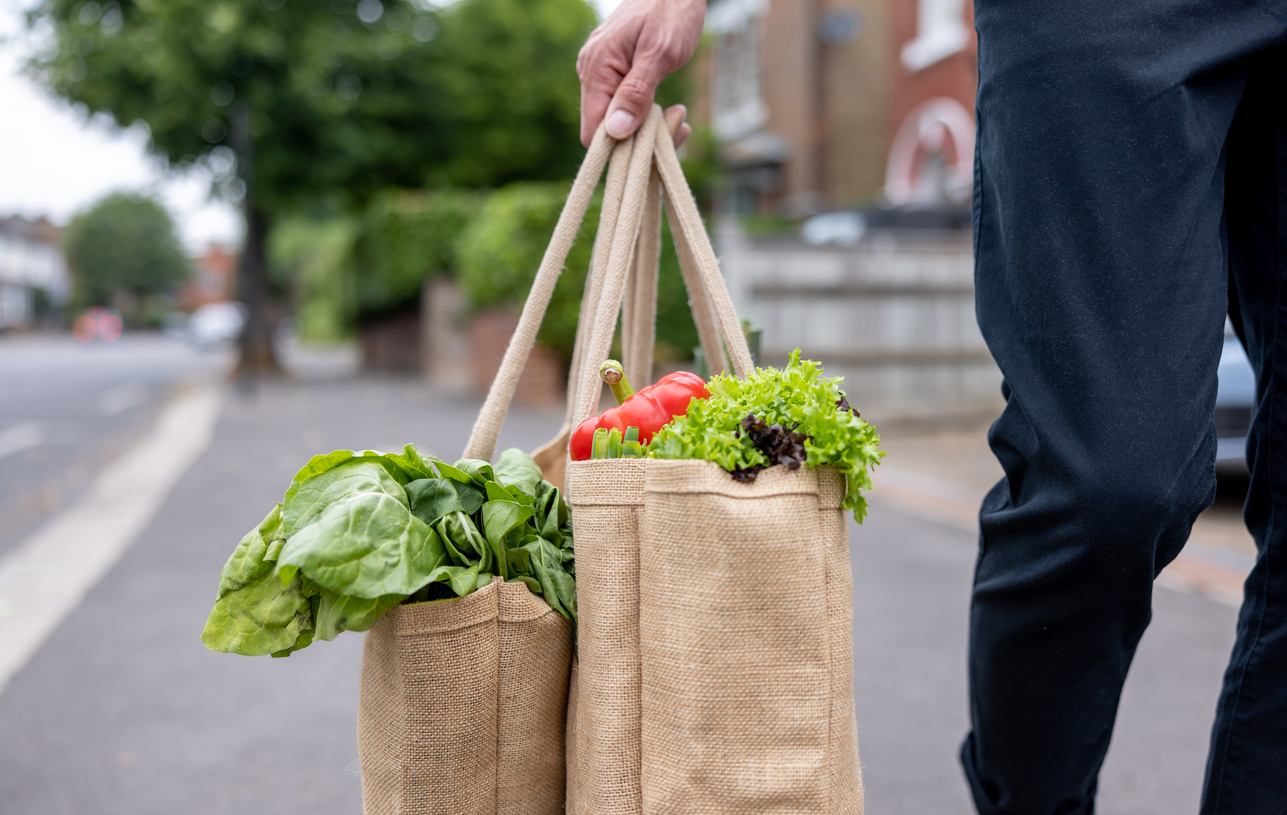 Close-up on a man carrying a shopping bag with groceries on his way home - domestic life concepts