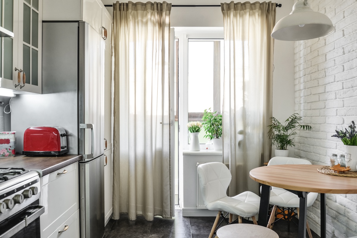 An empty kitchen with sheer curtains.