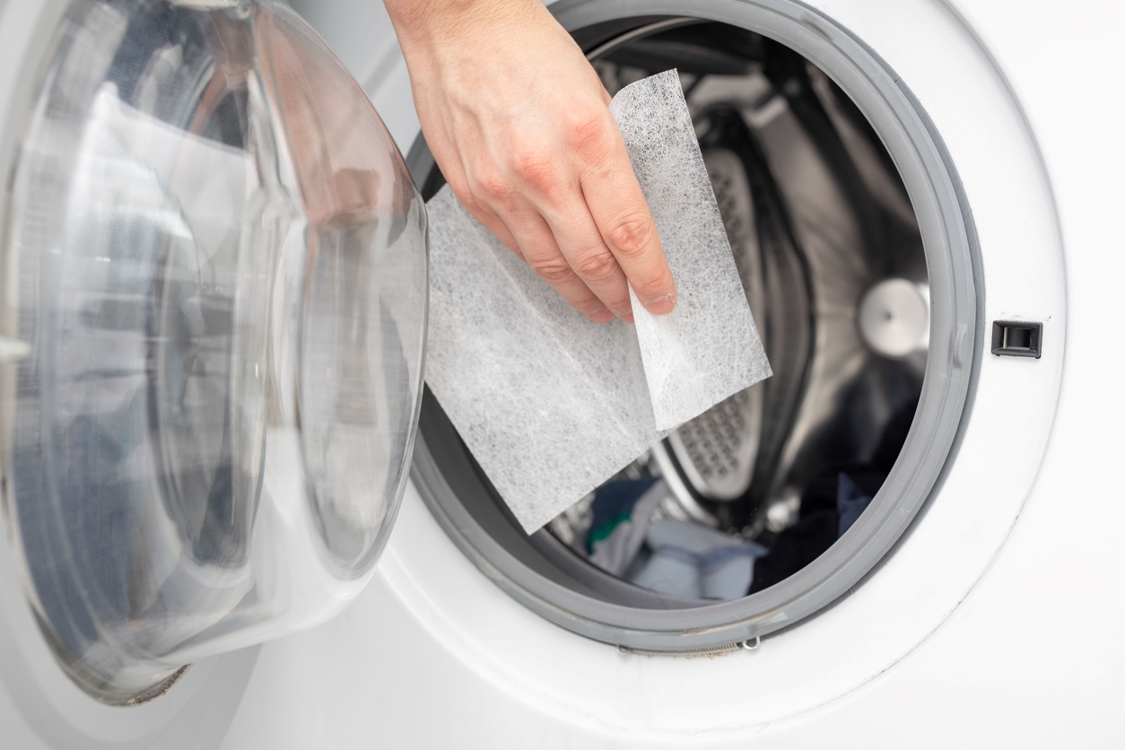 Person putting dryer sheet in dryer