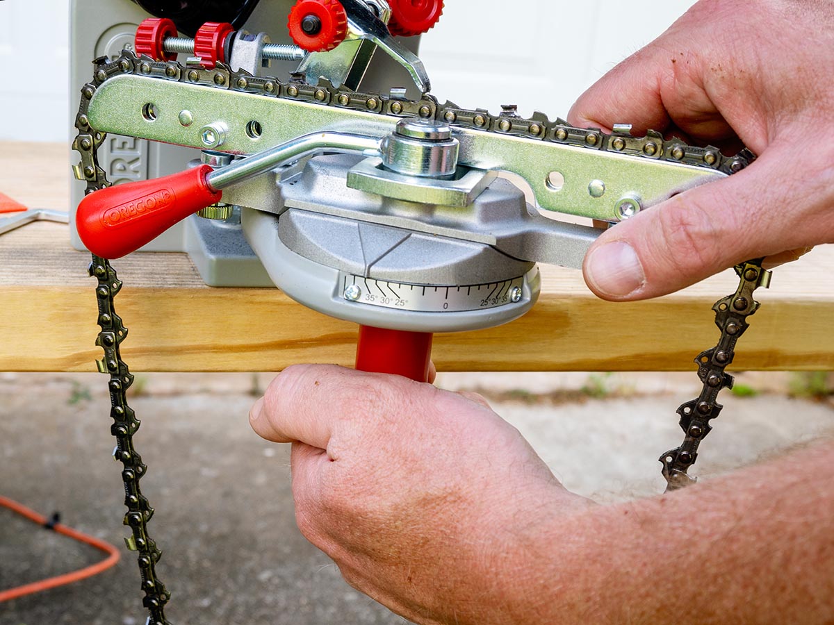 A person making an adjustment to the settings on the Oregon 410-120 Bench Grinder Chain Sharpener during testing.