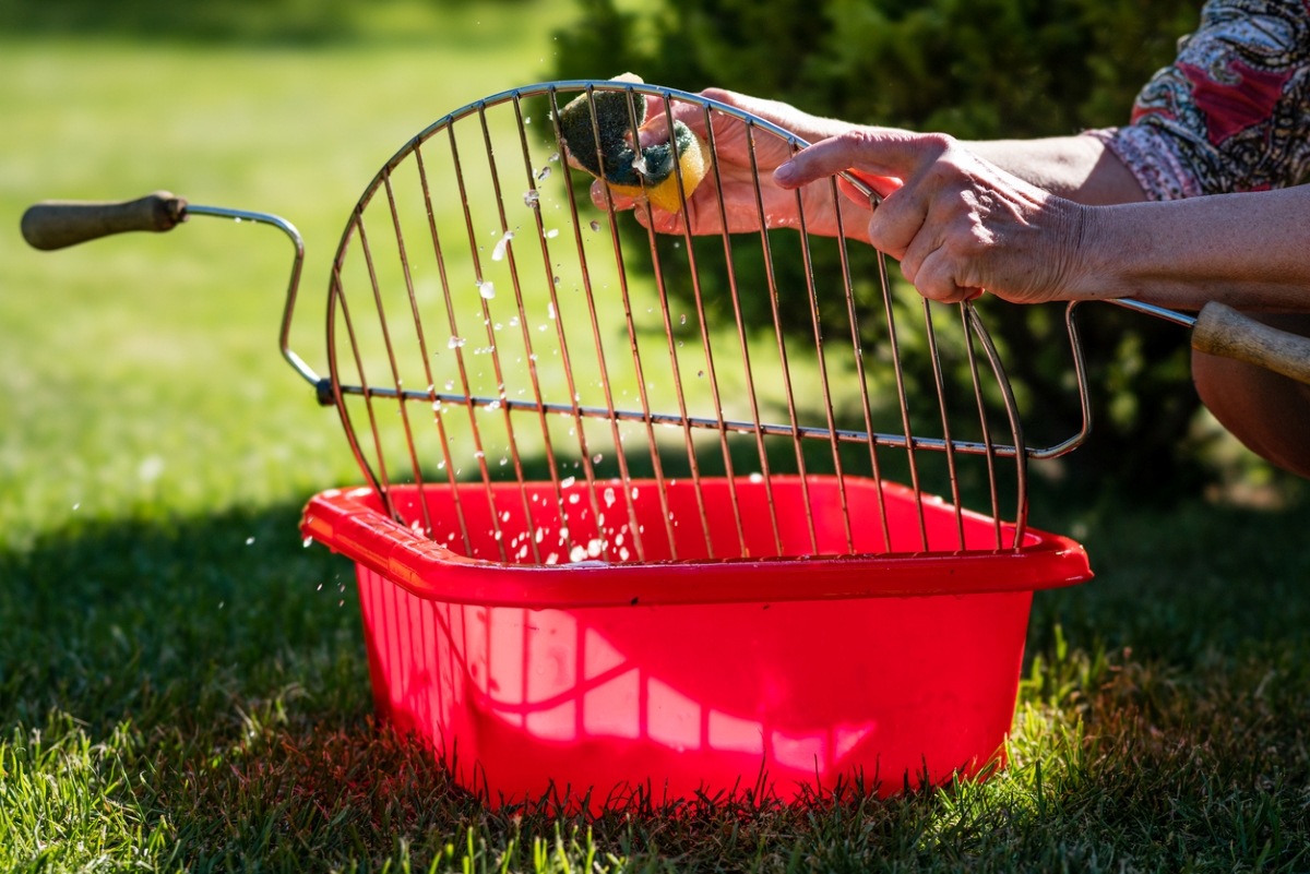 Person cleaning grill with sponge