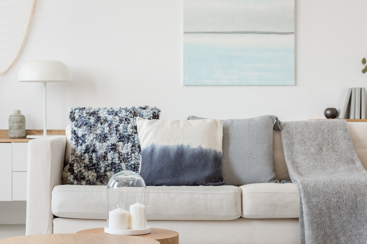 white couch in light colored living room with blue pillows and blankets