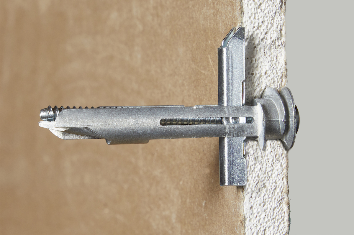 Side view of a self-drilling toggle drywall anchor in drywall. 