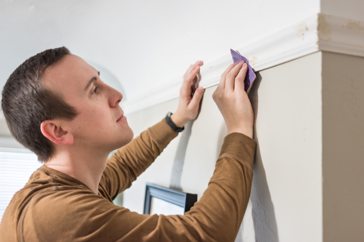 Man looking at small holes in wall trim.