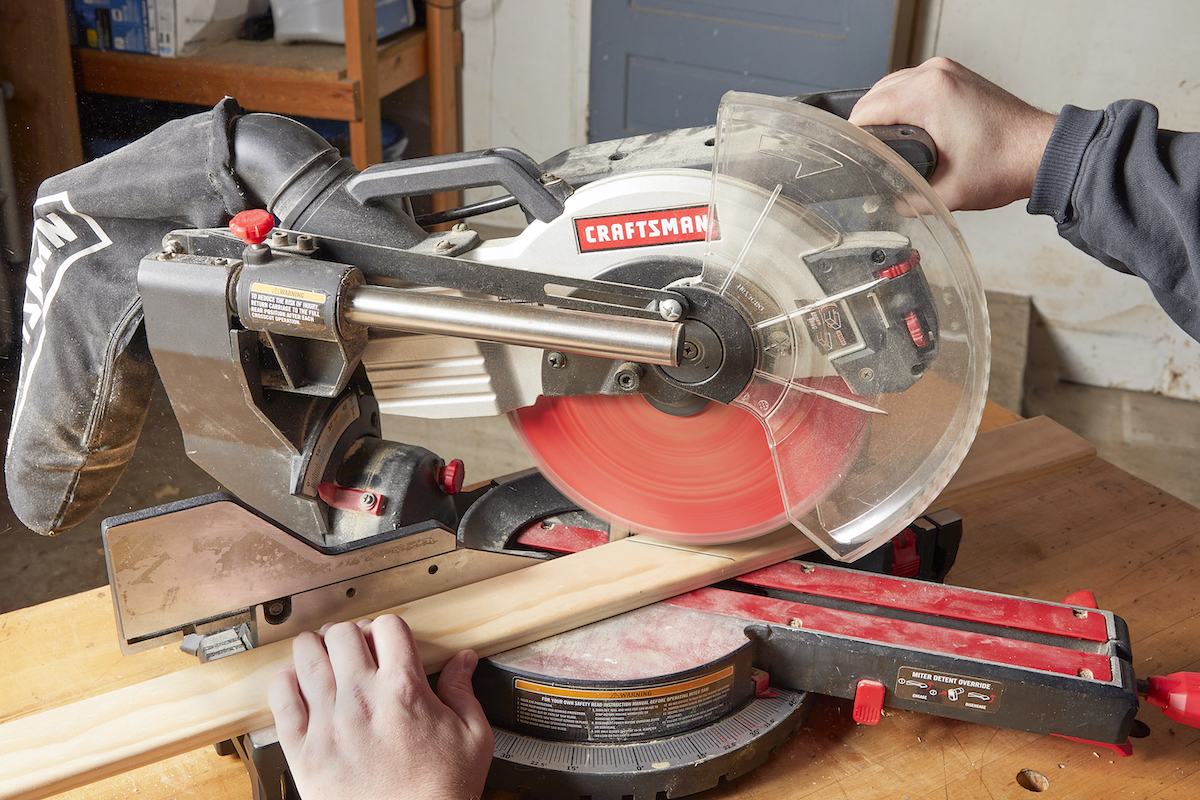 Man putting a marked workpiece on a miter saw.