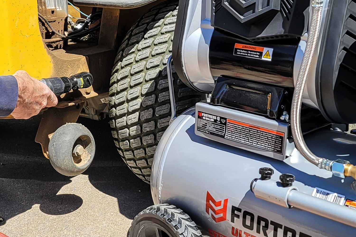 A person using the Harbor Freight Fortress air compressor to power a pneumatic tool