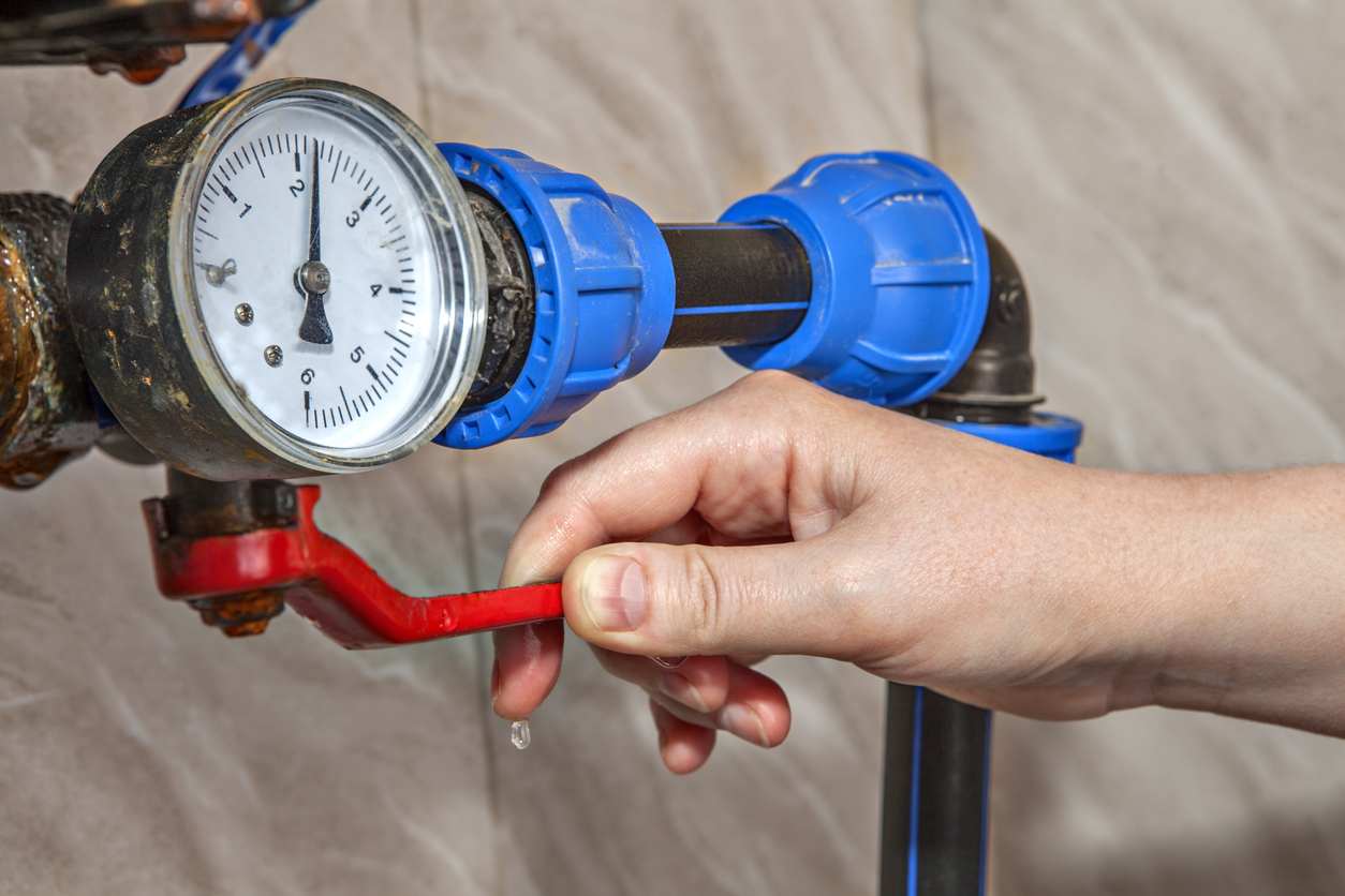 Person turning the lever on a home's main water valve.