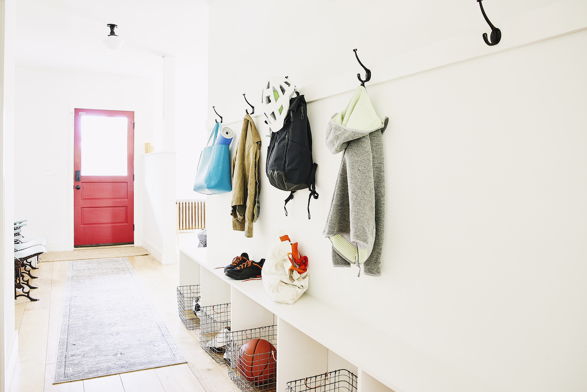 Wide shot of coats bags and shoes in entryway of home with a red front door.